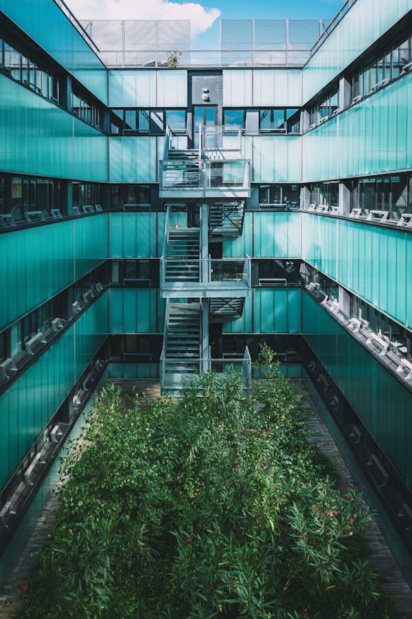 Immeuble de bureaux durables avec façades vitrées et jardin intérieur, exemple d’actif tertiaire valorisé par Tquarter, éligible aux subventions pour immobilier professionnel éco-performant.